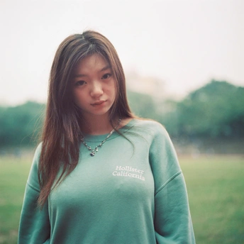 一位穿着绿色运动衫的年轻女子站在田野中