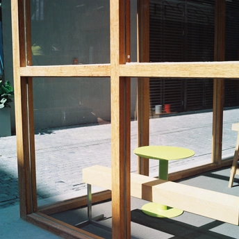 一张木椅子坐在建筑物旁边的一张绿色桌子旁边