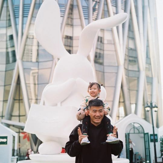 一个男人抱着一个小男孩 站在一只兔子和其他人的雕塑前拍照。