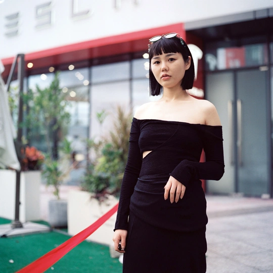 一位穿着黑色连衣裙的女人站在一条红色的地毯上