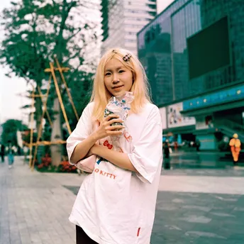一个穿着白色衬衫的年轻女子站在滑板车上拿着一杯东西
