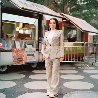 一位穿着西装的女性站在一辆食品推车前面