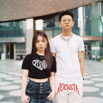 一个小男孩和一个小女孩站在一栋建筑前 一个男子站在他们前面。