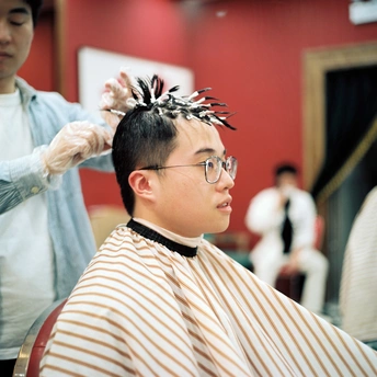 一个年轻男子在理发店由一位女士理发。