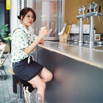 一个年轻女子坐在餐厅或酒吧的柜台前 手里拿着一杯咖啡。