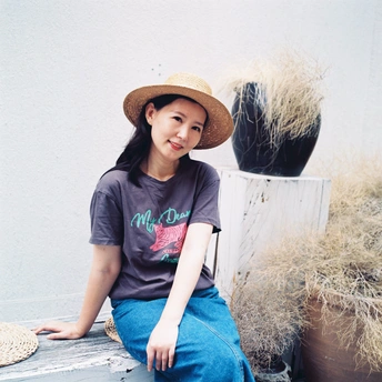 一个穿着T恤和牛仔裤的年轻女子坐在长凳上 戴着草编帽子。