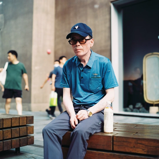 一个穿着蓝色衬衫和帽子坐在木凳上的男人