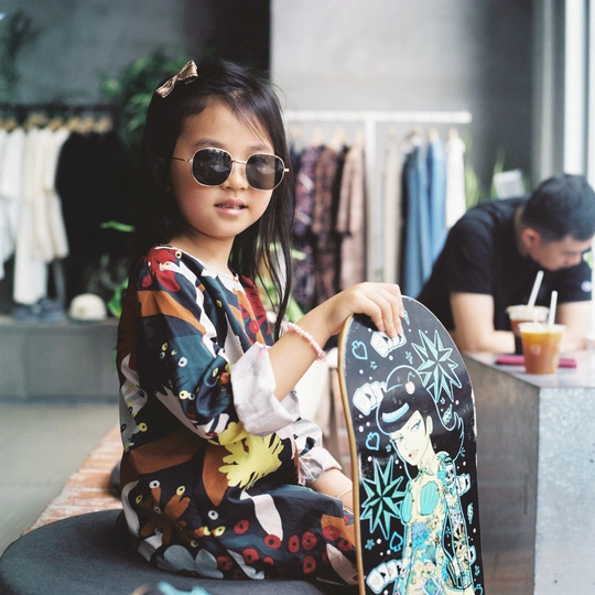 一个戴太阳镜的年轻女孩抱着一个小包坐在椅子上