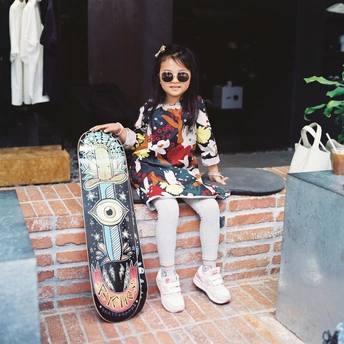 一个小女孩坐在砖头边缘 手里拿着一个小雪板。