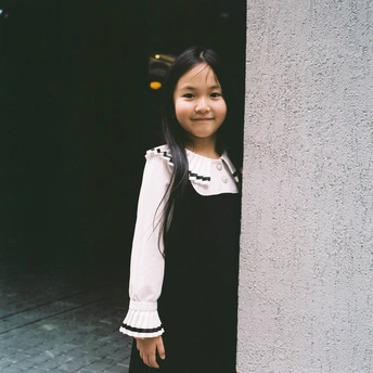 一个小女孩穿着裙子靠在建筑物的墙上