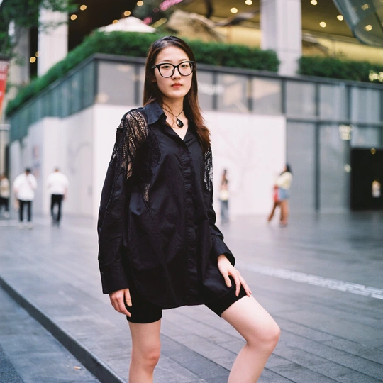 一个戴眼镜穿黑色连衣裙的年轻女子走在人行道上