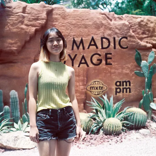 一位穿黄衬衫的女士站在一个仙人掌标志前面