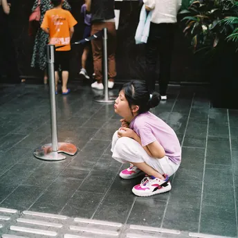 一个女孩坐在地板上 光着脚 其他人在场观看。