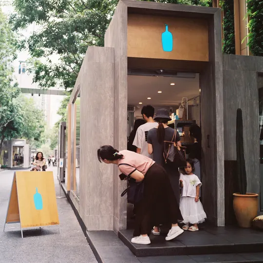 一位妇女站在商店外 带着一个小女孩和其他人向外看。