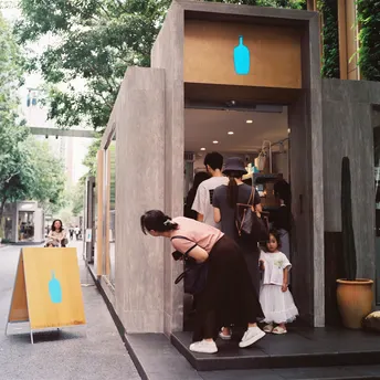 一位妇女站在商店外 带着一个小女孩和其他人向外看。