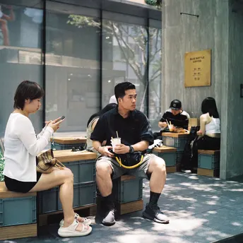 一个男人和一个女人坐在建筑物前的一张长椅上 同时看着他们的手机。