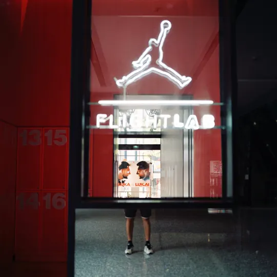 站在商店前 窗户里有红氖灯招牌的男子