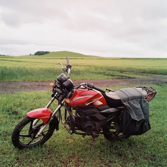 一辆红色的摩托车 背包放在草地上