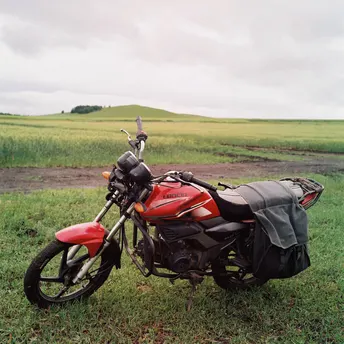 一辆红色的摩托车 背包放在草地上