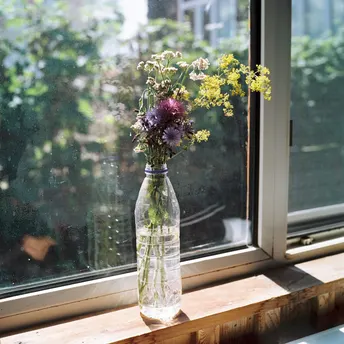 一瓶花清晰地装在窗台上 旁边就是窗户。