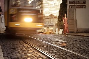 一位夜间在轨道上行走的女士 带着一辆黄色火车。