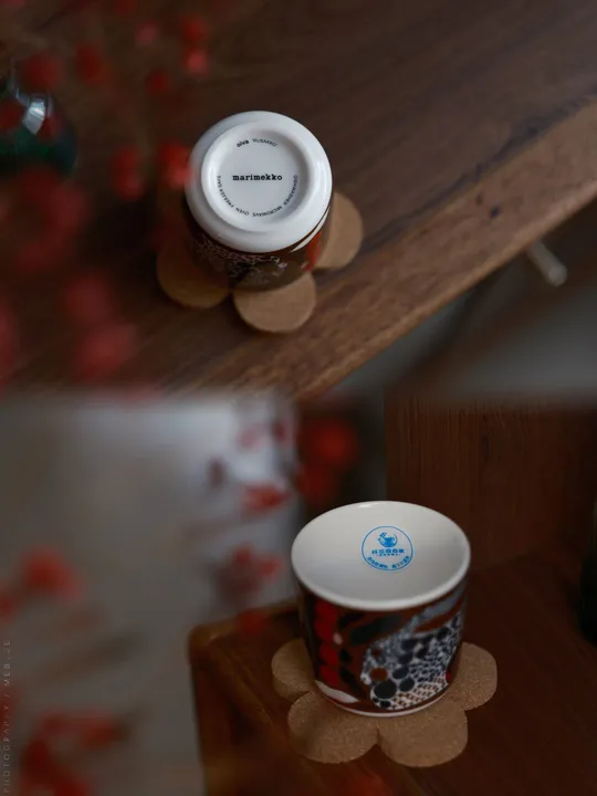 一小杯咖啡放在一个木制书架上 书架上面放着一个木制桌子 桌子上还放着花。