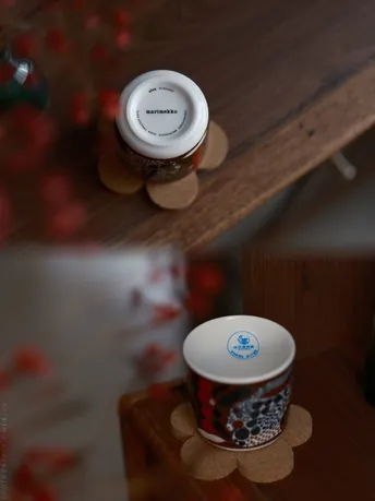 一小杯咖啡放在一个木制书架上 书架上面放着一个木制桌子 桌子上还放着花。