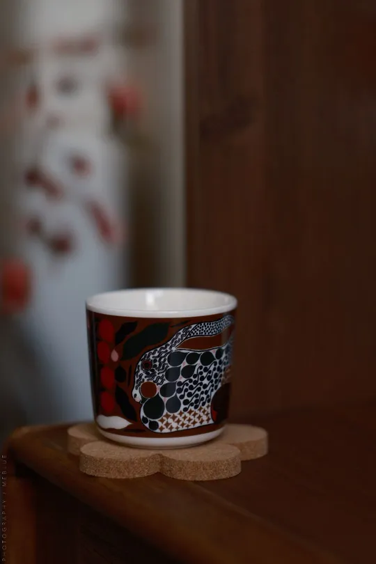 一个红白相间的咖啡杯上有一个骷髅和十字架 放在木制柜台上。