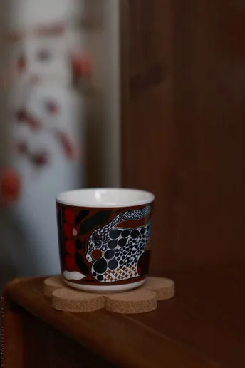 一个红白相间的咖啡杯上有一个骷髅和十字架 放在木制柜台上。