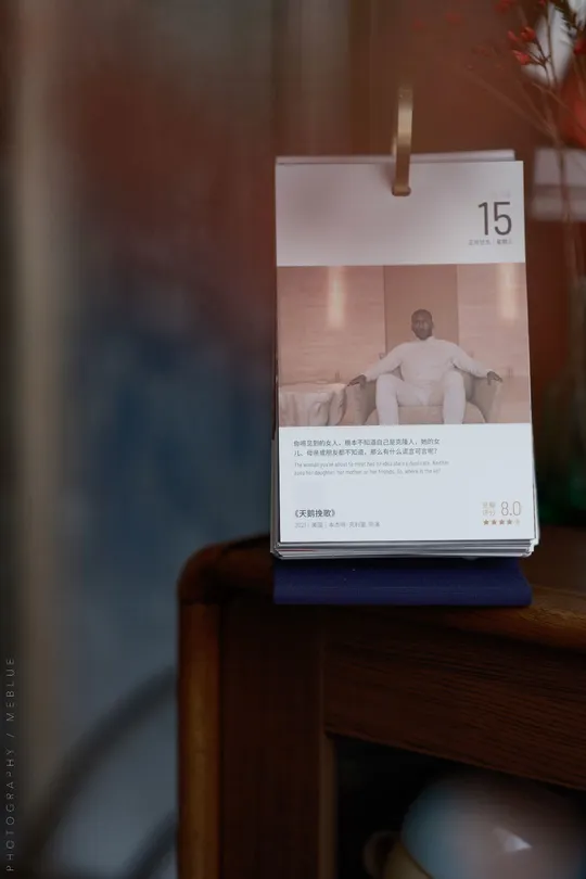 一本书放在一个花瓶旁边 花瓶里插着花 还有一张卡片。