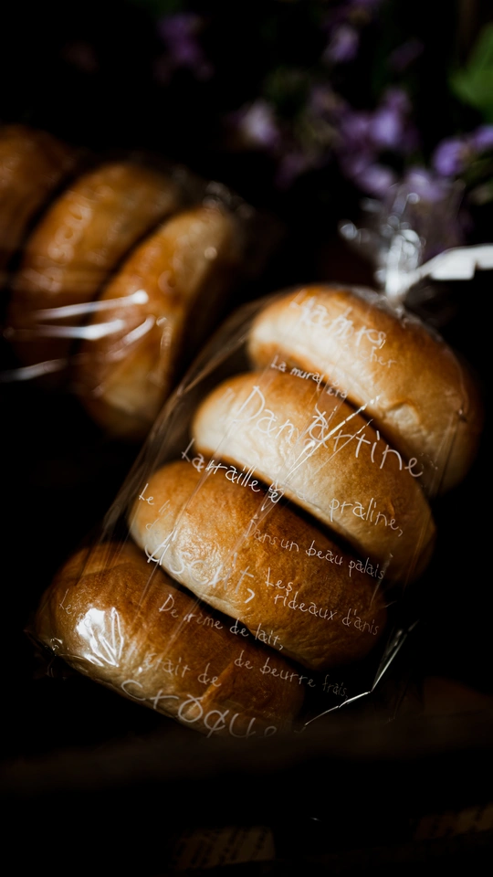 桌子上的一条用保鲜膜包着的面包 旁边放着一些花