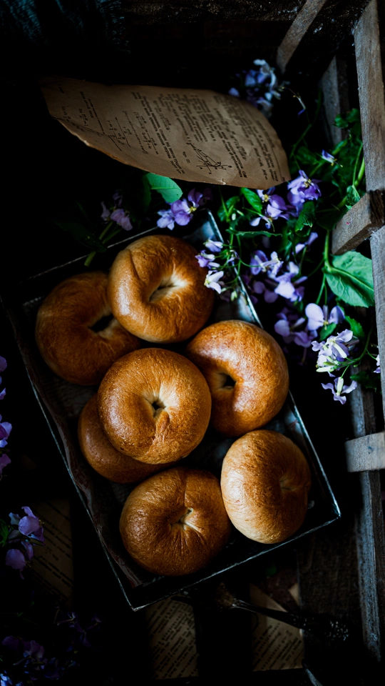 一个装满桔子和苹果的木箱 旁边放着一些紫色的花