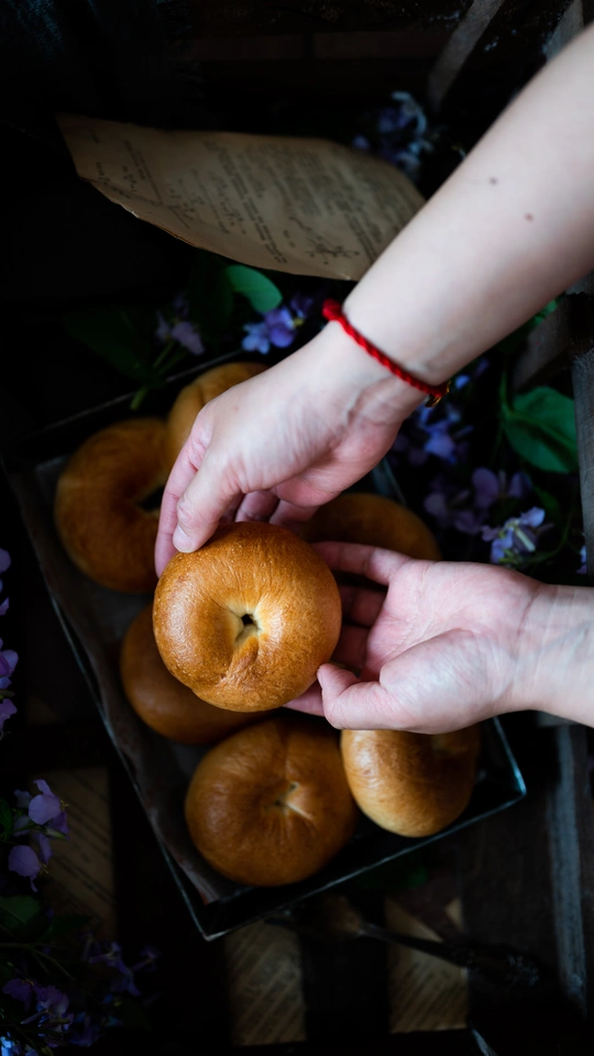 一个人手里拿着一个苹果 放在桌子上的一篮橙子和一盒水果上