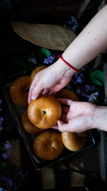 一个人手里拿着一个苹果 放在桌子上的一篮橙子和一盒水果上