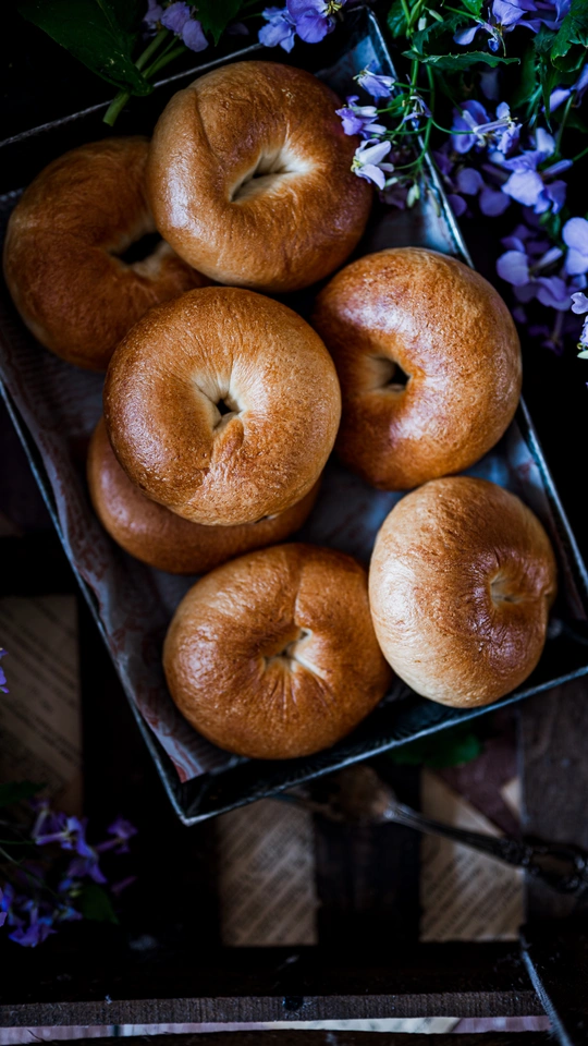 放着一些糕点的托盘 旁边放着一些花和一碗苹果