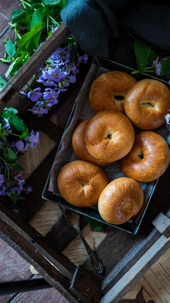 一个装满新鲜甜甜圈的木箱 旁边放着一个装满鲜花的木箱