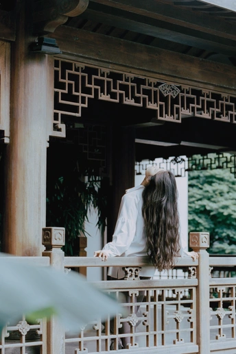 一个女人坐在长长的阳台上 看着外面的白色神殿