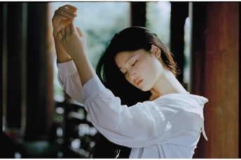 一个穿着白衬衫、眼睛闭在窗边的年轻女子