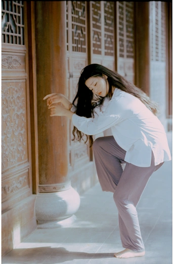 一个穿着白裤子的年轻女子靠在一栋楼的门上