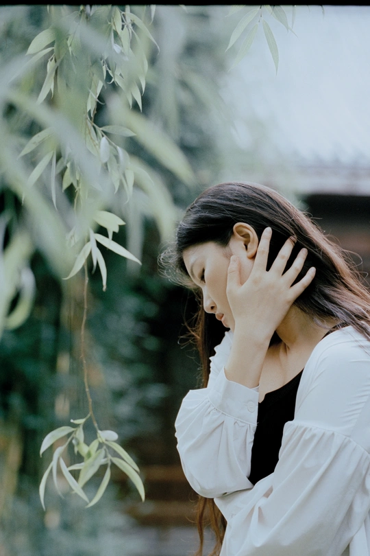 一位身穿白衬衫的年轻女子双手捂着脸 遮住眼睛