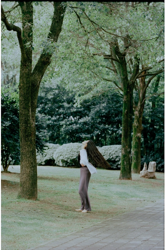 一个女人穿过一个背景是树的公园