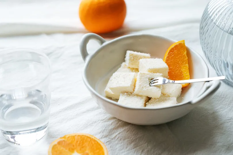 一个带有食物的白色桌子 一个玻璃杯和水 还有橙子。