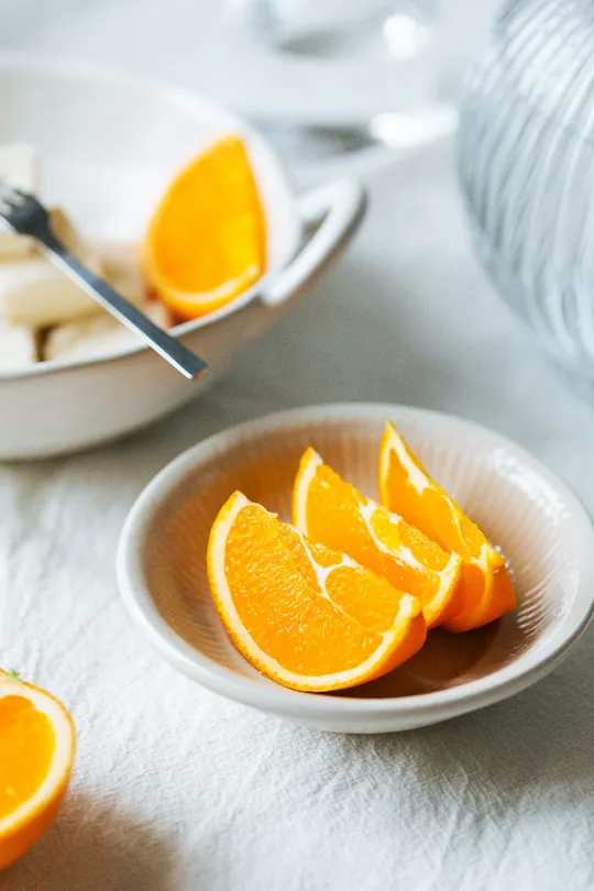 oranges and bananas sit on a white plate with a fo