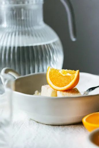 一碗食物 一把勺子 一个水壶 放在一张白色的桌子上