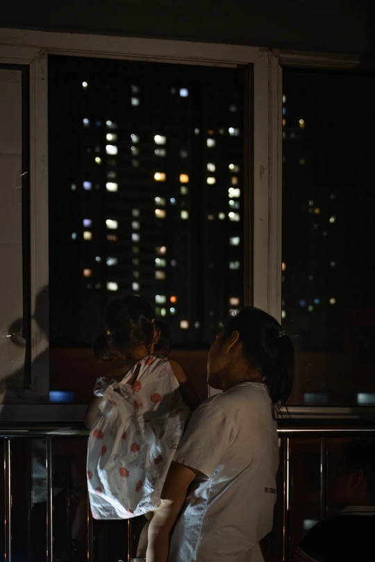 一些人站在阳台上 晚上看着一个亮着灯的城市。
