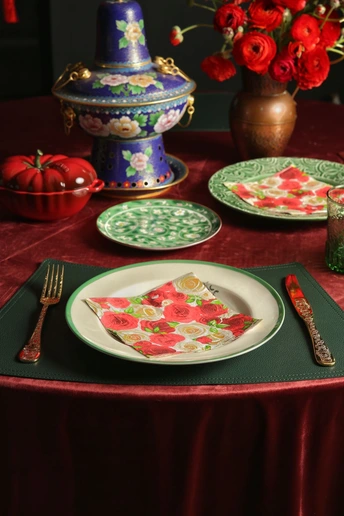 红色餐具、绿色餐巾和红色花朵的餐桌