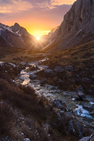 山脉上美丽的日出或日落 前景中有河流和溪流