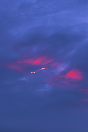 粉红色云彩映衬下的多彩晚霞 天空中一架红色飞机翱翔。
