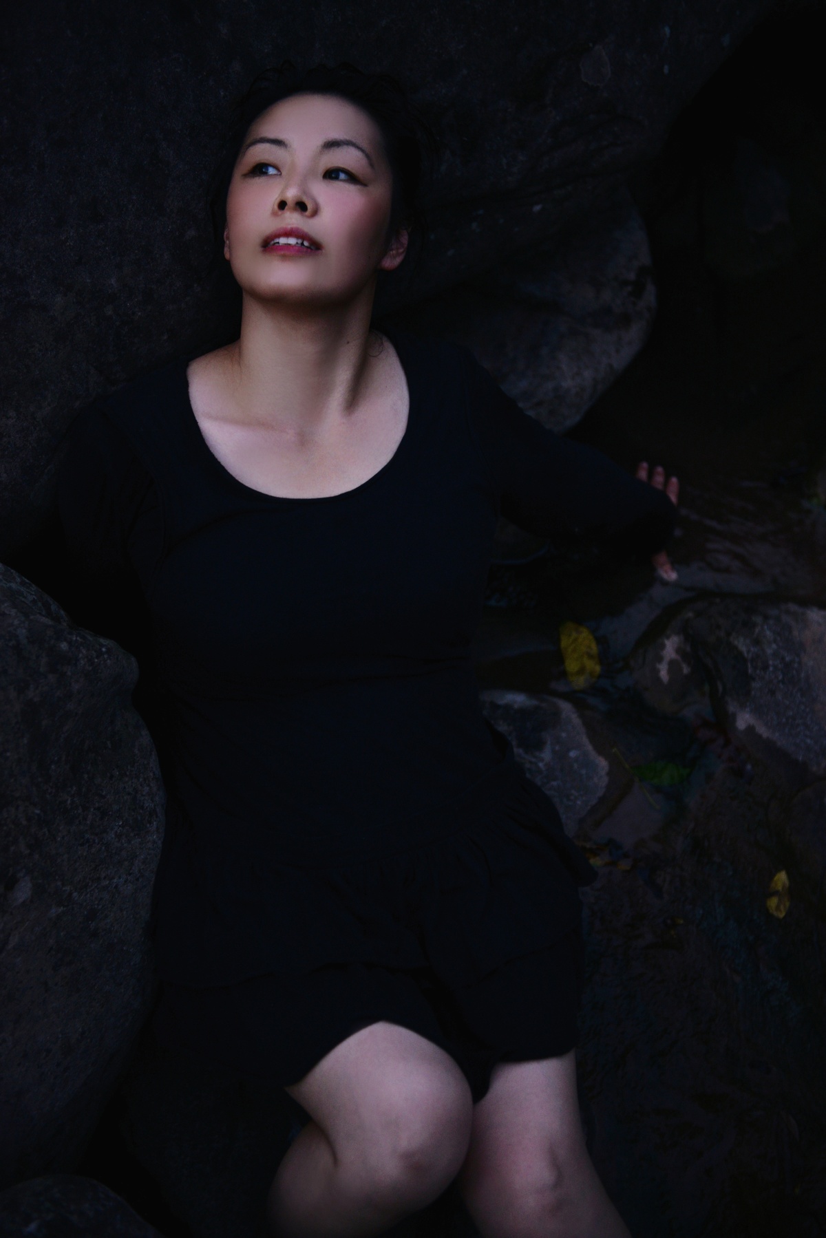 一个穿着黑色连衣裙的女人坐在岩石上
