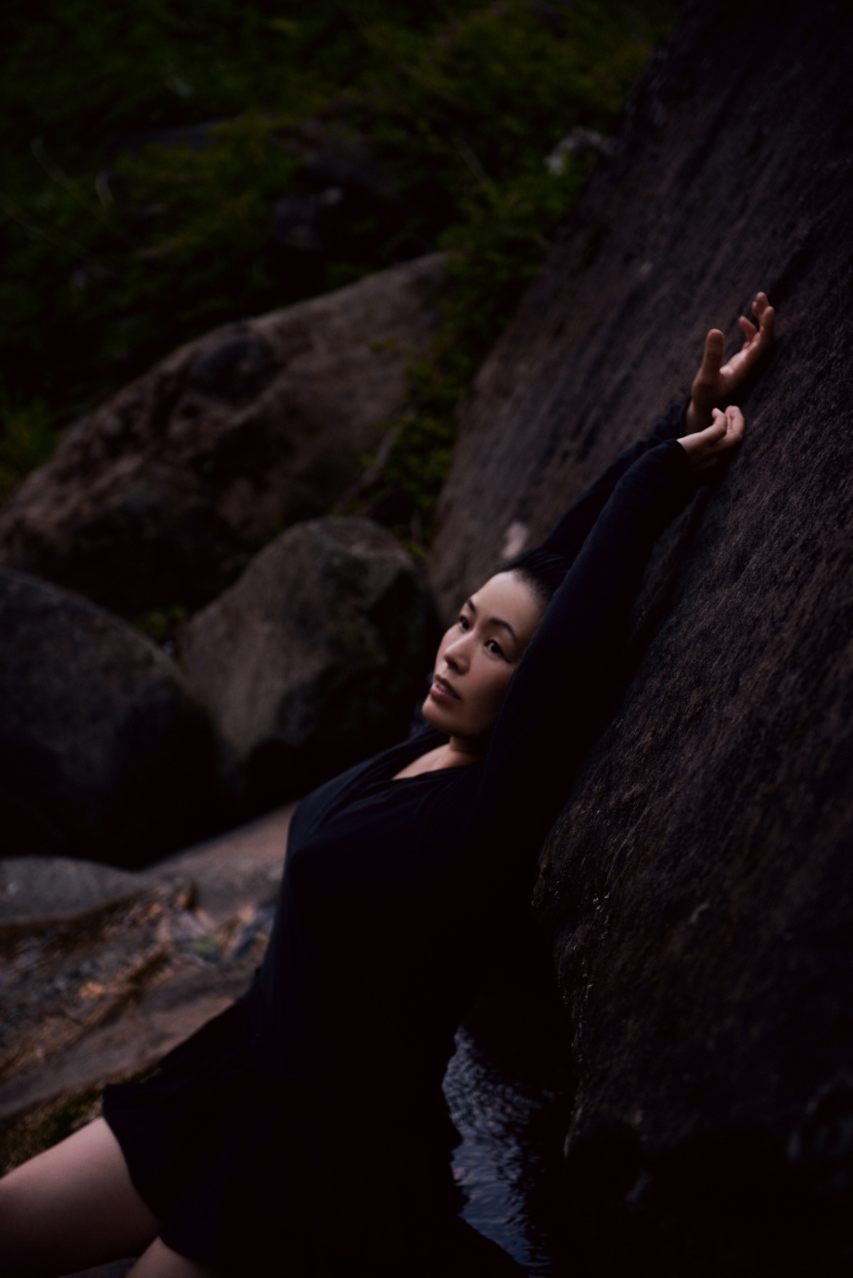 一个穿着黑色连衣裙的美女躺在岩石上